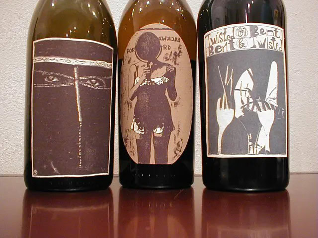 Drei Flaschen Wein mit künstlerischen Etiketten.